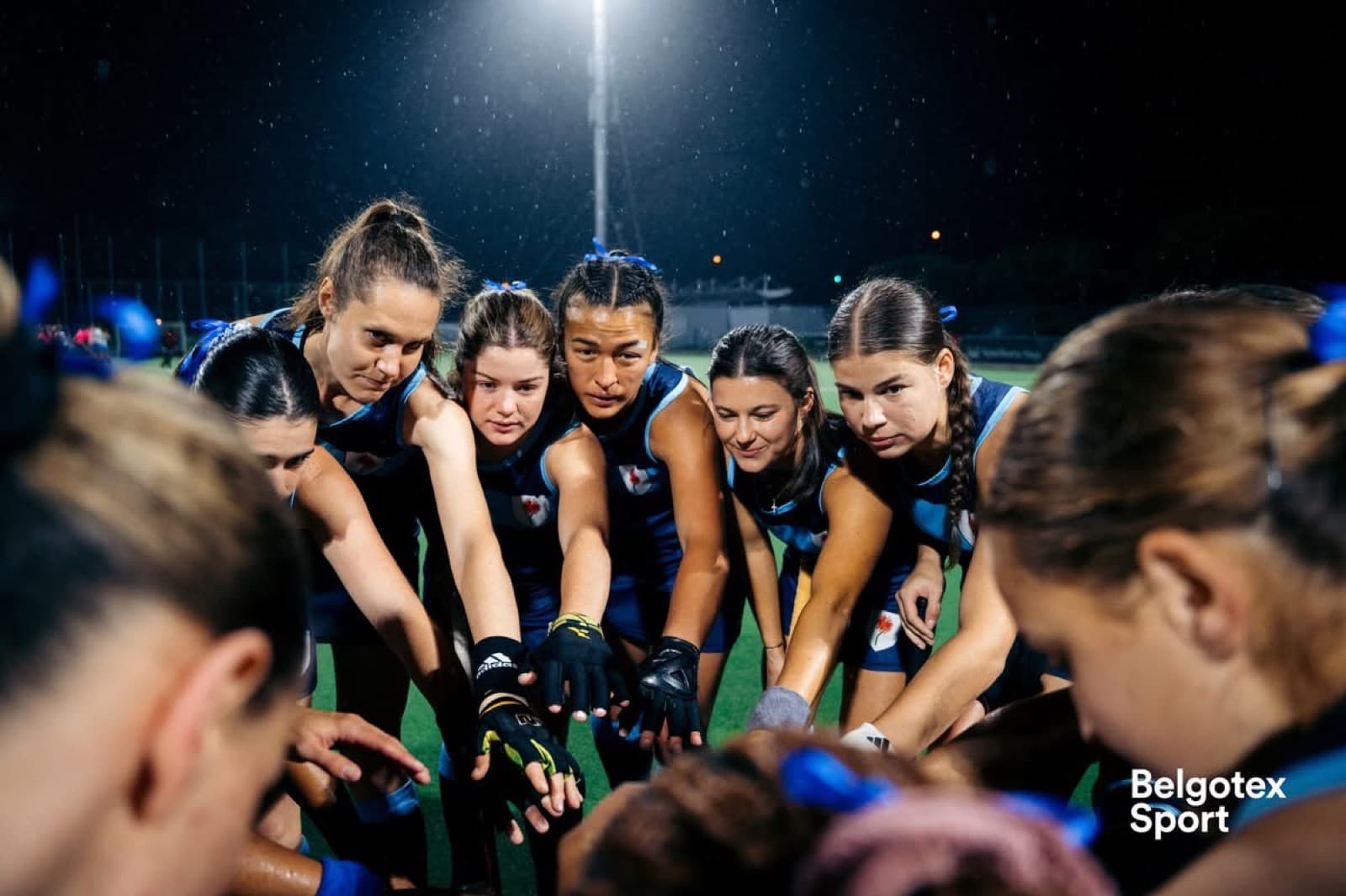 A hockey team huddled together under floodlights